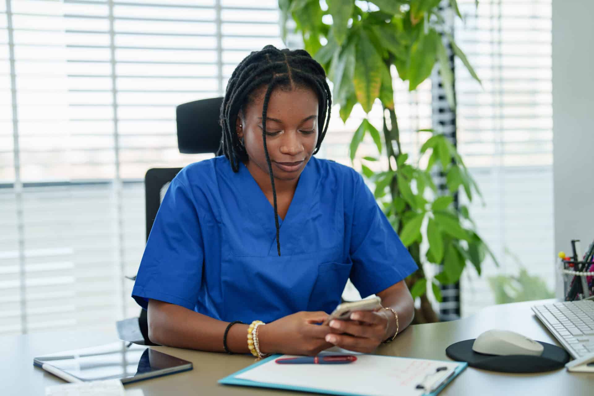 a woman in blue scrubs looking at a phone